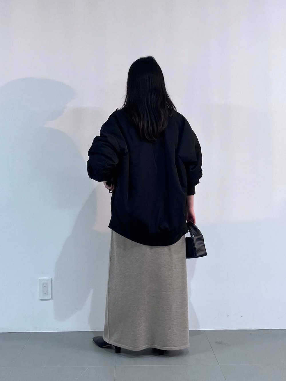 ブラック系のトートバッグ、ブラック系のMA-1、ベージュ系のワンピースを着用したレディースの秋コーディネートの3枚目の写真