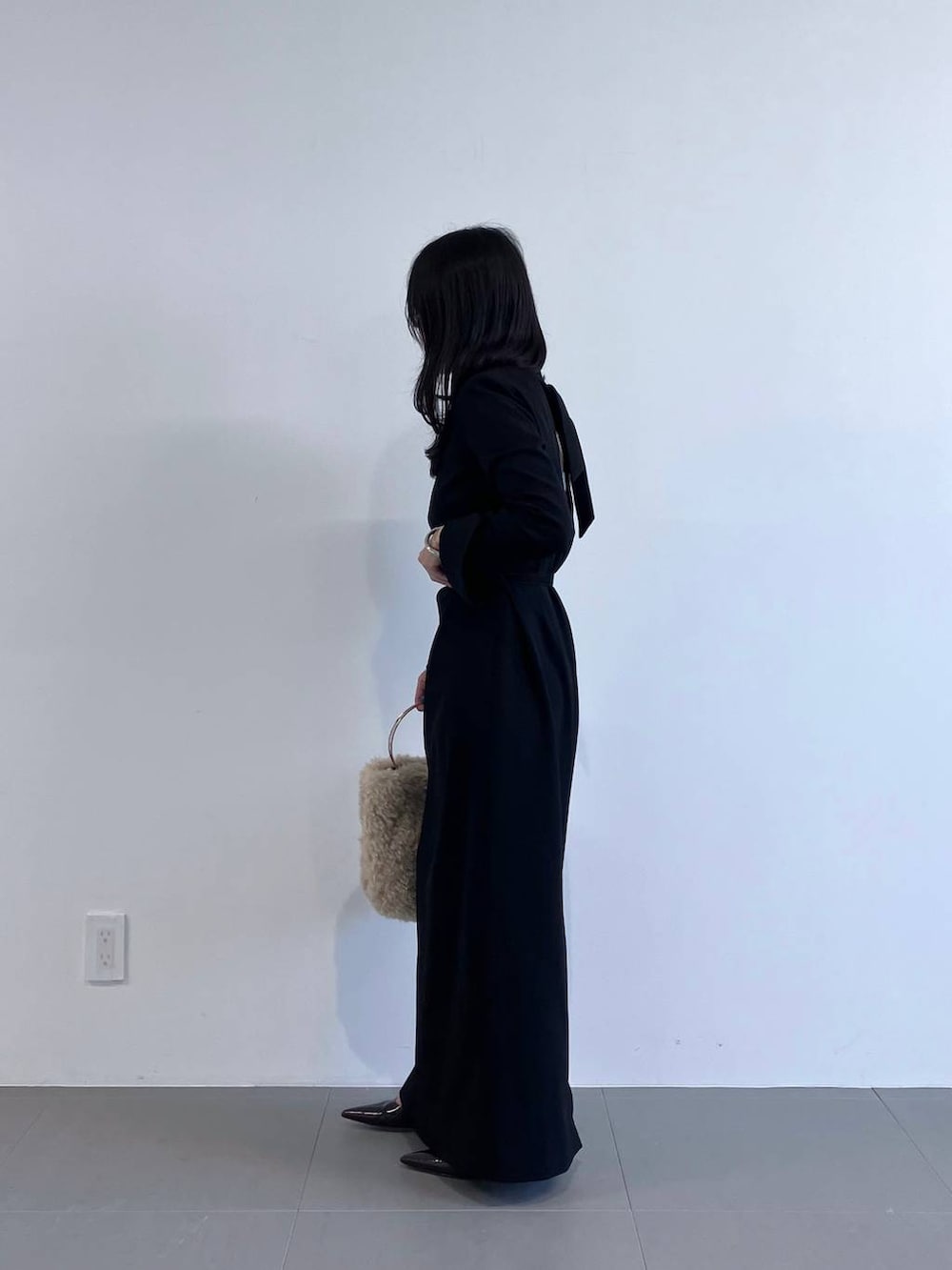 ホワイト系のハンドバッグ、ブラック系のワンピースを着用したレディースの秋コーディネートの3枚目の写真