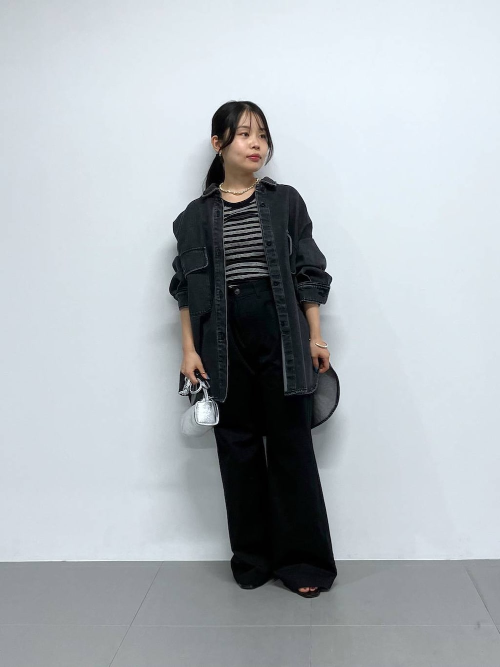 シルバー系のショルダーバッグ、ブラック系のチノパンツ、ブラック系のTシャツ/カットソーを着用したレディースの秋コーディネートの2枚目の写真