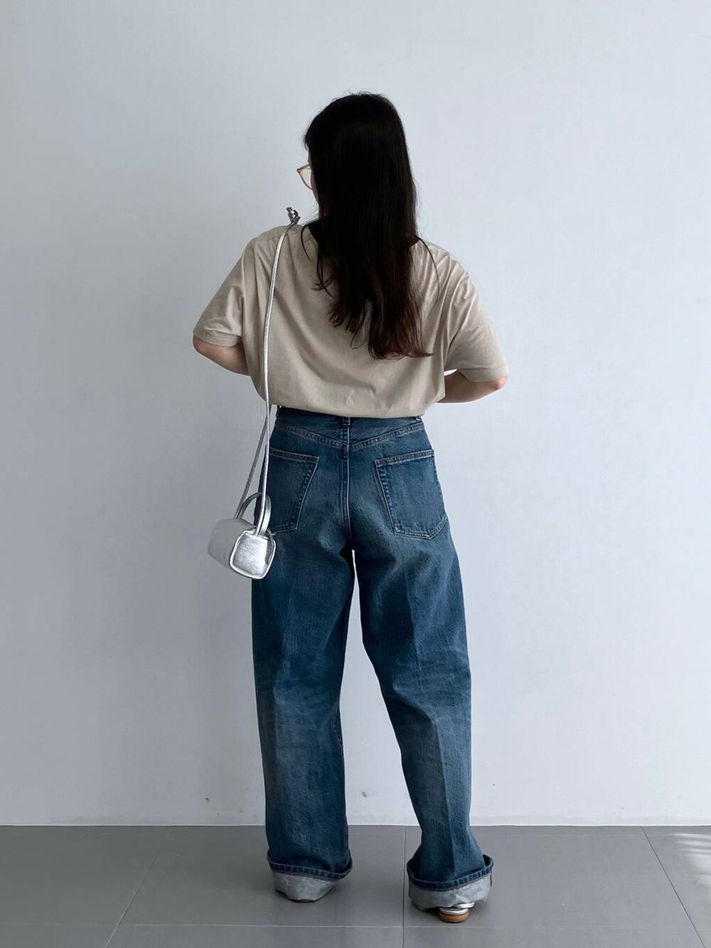 ブルー系のデニムパンツ、シルバー系のパンプス、ベージュ系のTシャツ/カットソーを着用したレディースの夏コーディネートの4枚目の写真