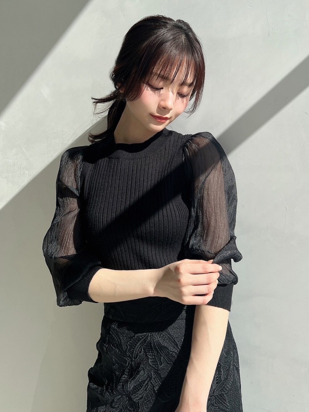 ブラック系のニット/セーター、ブラック系のスカート、ピンク系のトレンチコートを着用したレディースの春コーディネートの2枚目の写真