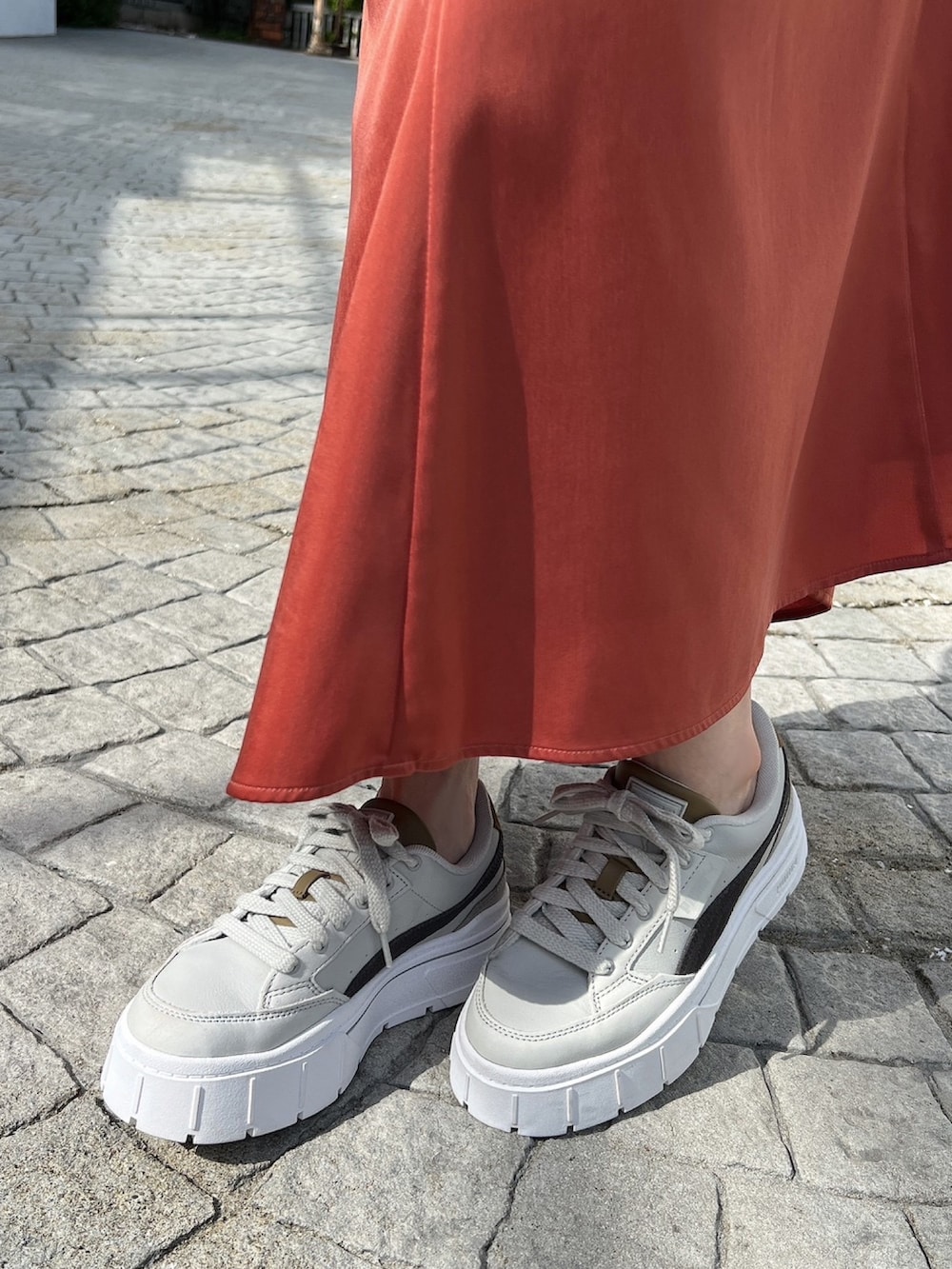 グレー系のスニーカー、ホワイト系のニット/セーター、オレンジ系のスカートを着用したレディースの冬コーディネートの5枚目の写真