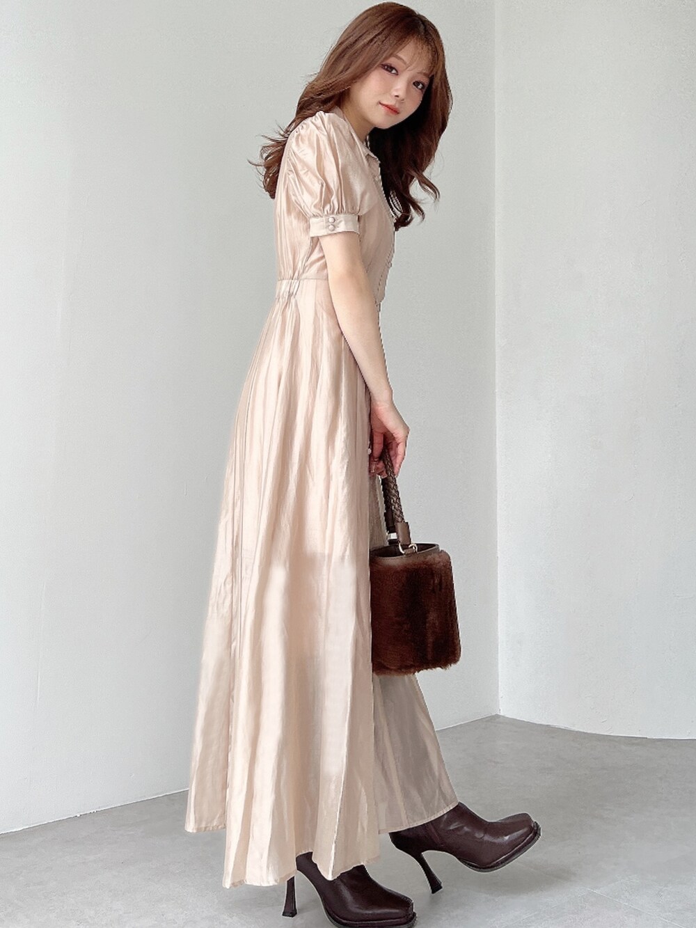 ベージュ系のワンピース、ブラウン系のショルダーバッグ、ブラウン系のブーツを着用したレディースの夏コーディネートの2枚目の写真