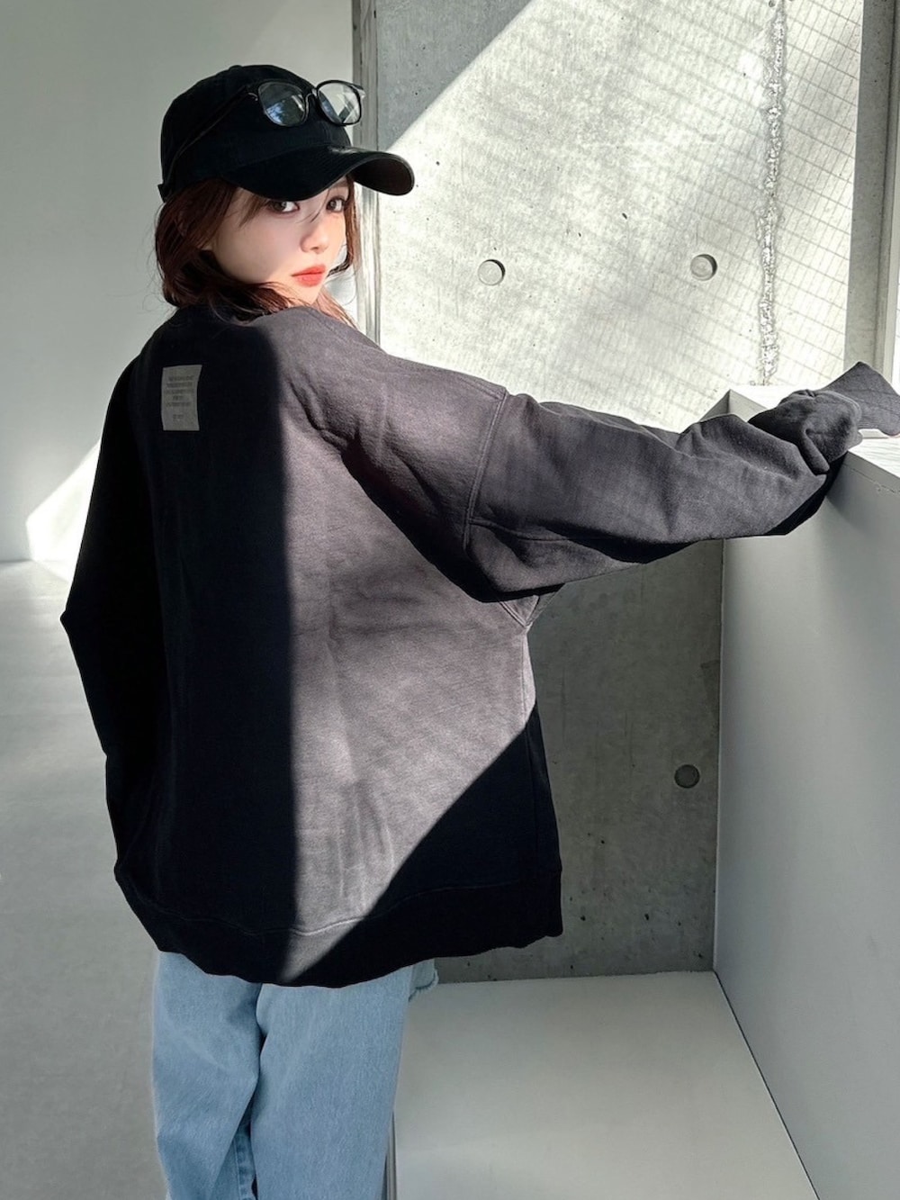 ブラック系のスウェット、ブルー系のデニムパンツを着用したレディースの春コーディネートの2枚目の写真