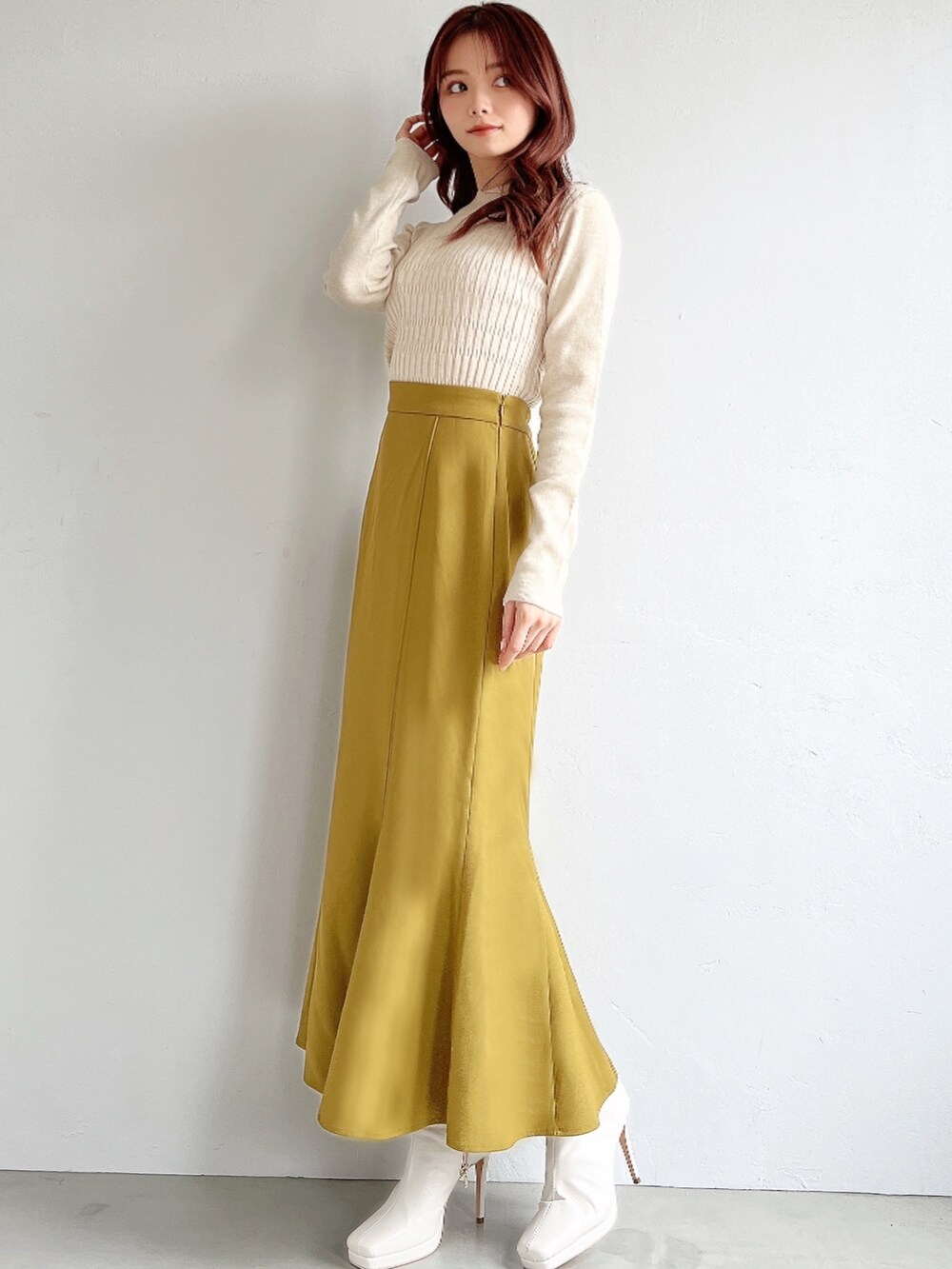 ブラウン系のスカート、ホワイト系のニット/セーター、ブラック系のチェスターコートを着用したレディースの冬コーディネートの4枚目の写真