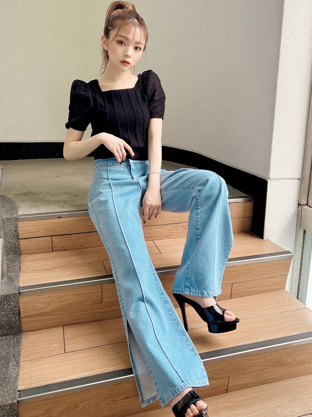 ブラック系のニット/セーター、ブラック系のサンダル、ブルー系のデニムパンツを着用したレディースの夏コーディネートの2枚目の写真