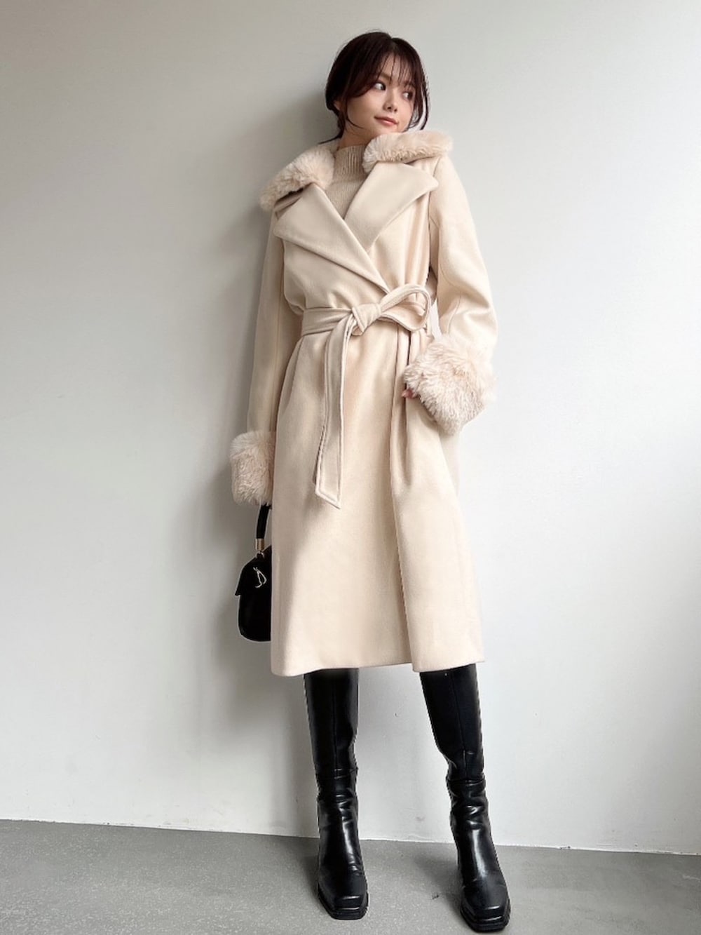 ホワイト系のその他アウター、ベージュ系のニット/セーター、ブラック系のハンドバッグを着用したレディースの冬コーディネートの5枚目の写真