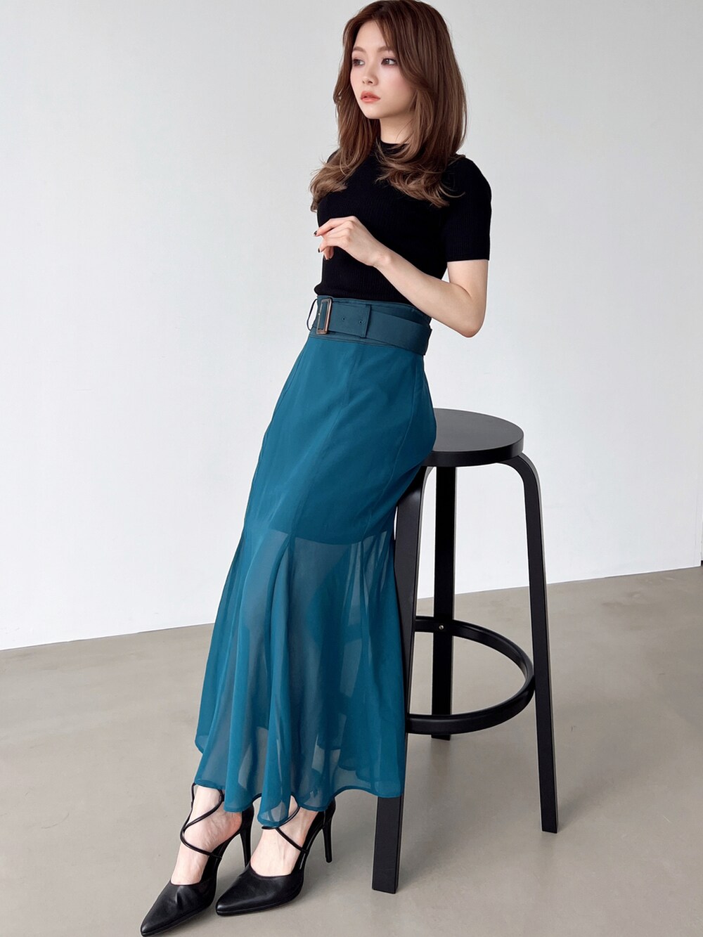 グリーン系のスカート、ブラック系のパンプス、ブラック系のニット/セーターを着用したレディースの夏コーディネートの3枚目の写真