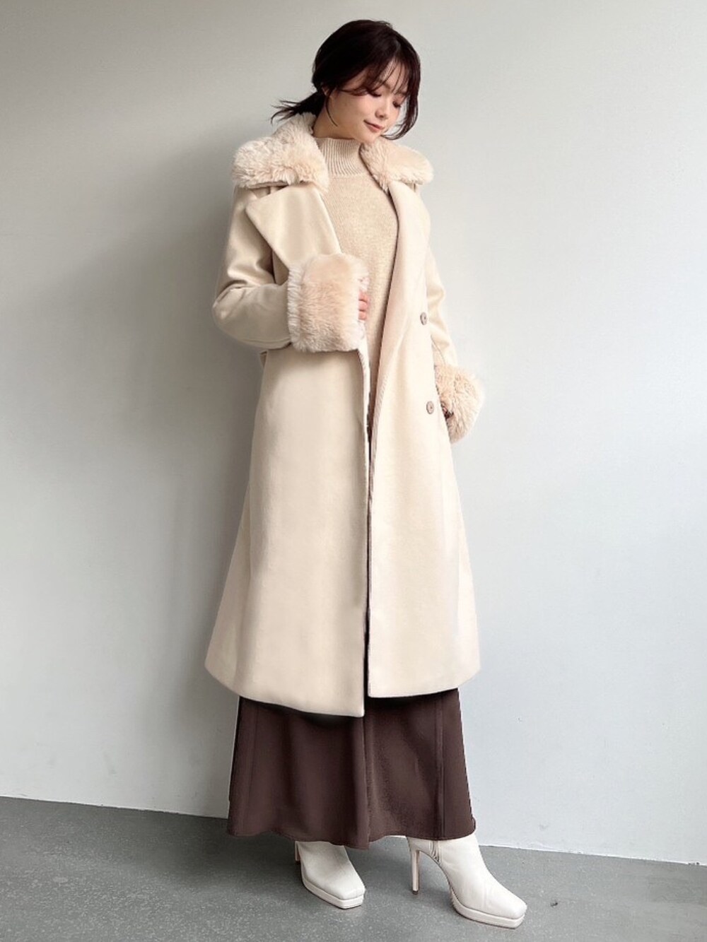 ホワイト系のその他アウター、ベージュ系のニット/セーター、ブラウン系のスカートを着用したレディースの冬コーディネートの4枚目の写真