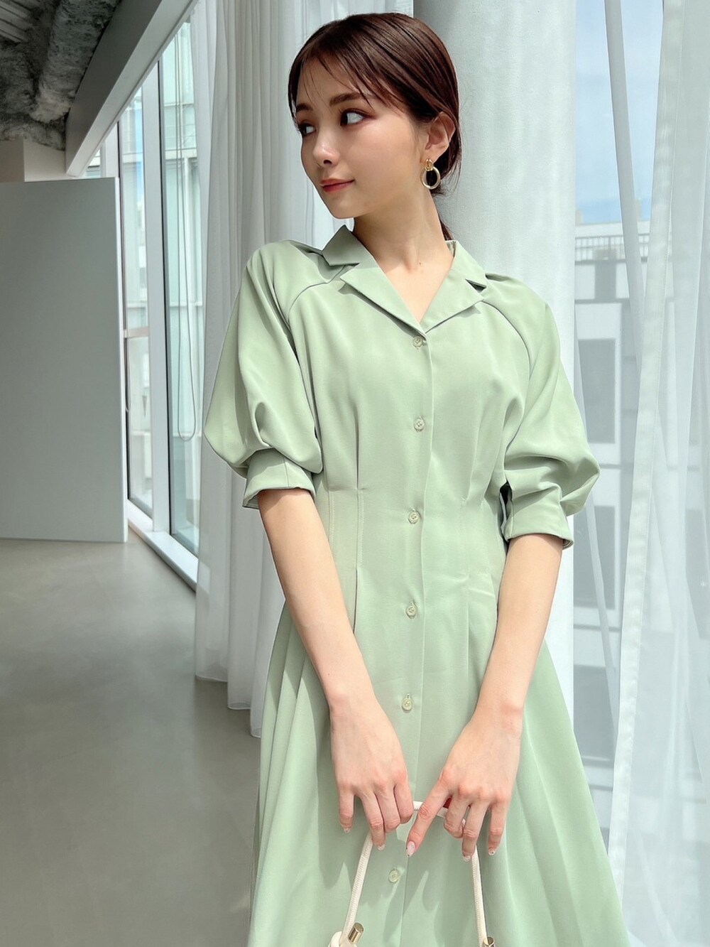 グリーン系のシャツワンピース、ホワイト系のサンダル、ホワイト系のハンドバッグを着用したレディースの春コーディネートの3枚目の写真