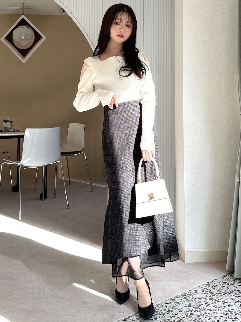 ホワイト系のニット/セーター、ブラック系のスカート、ホワイト系のハンドバッグを着用したレディースの冬コーディネートの2枚目の写真