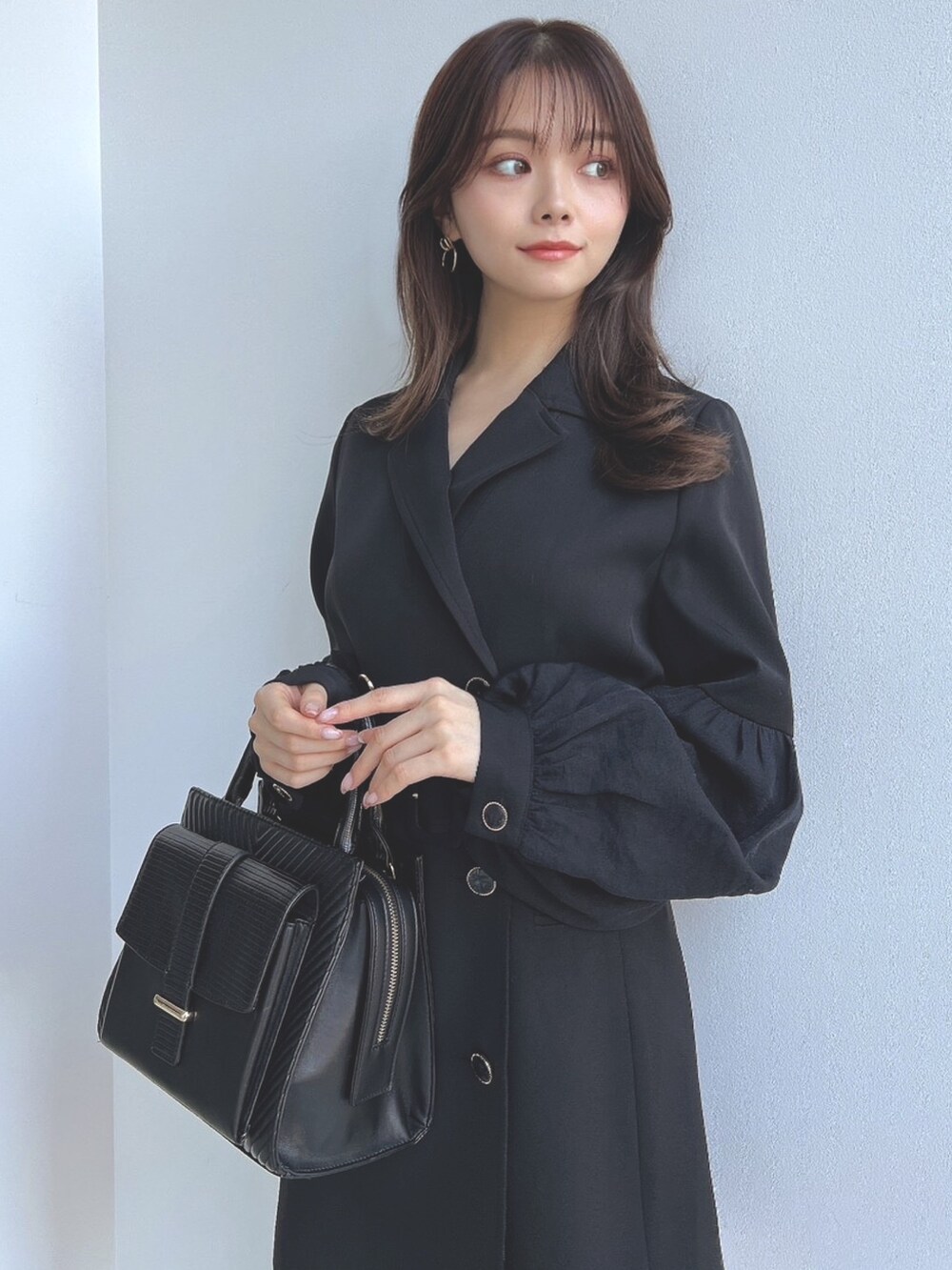 ブラック系のワンピース、ブラック系のハンドバッグを着用したレディースの冬コーディネートの2枚目の写真