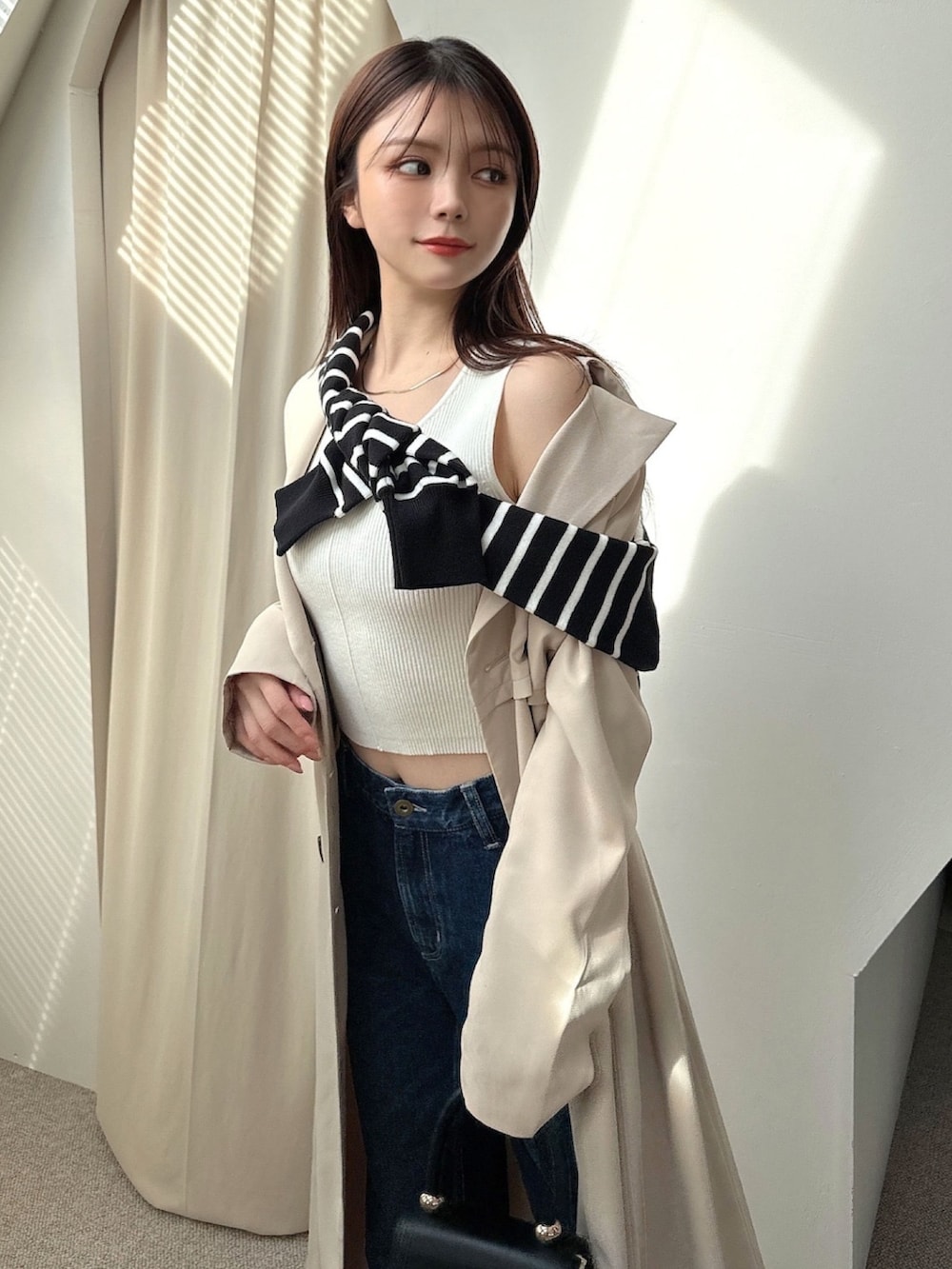 ベージュ系のトレンチコート、その他のカーディガン/ボレロ、ブルー系のデニムパンツを着用したレディースの冬コーディネートの4枚目の写真