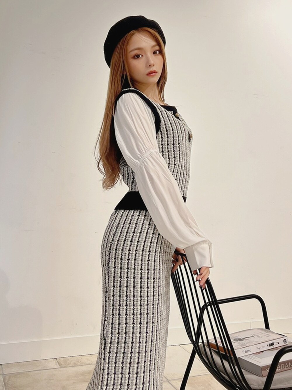 ブラック系のベスト、ホワイト系のブーツ、ブラック系のスカートを着用したレディースの秋コーディネートの2枚目の写真