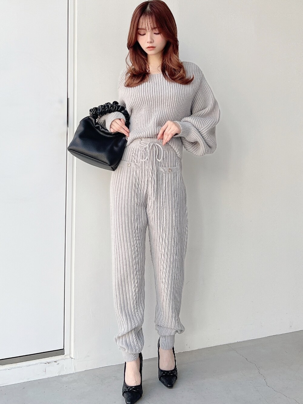 グレー系のニット/セーター、グレー系のその他パンツ、ブラック系のハンドバッグを着用したレディースの秋コーディネートの2枚目の写真