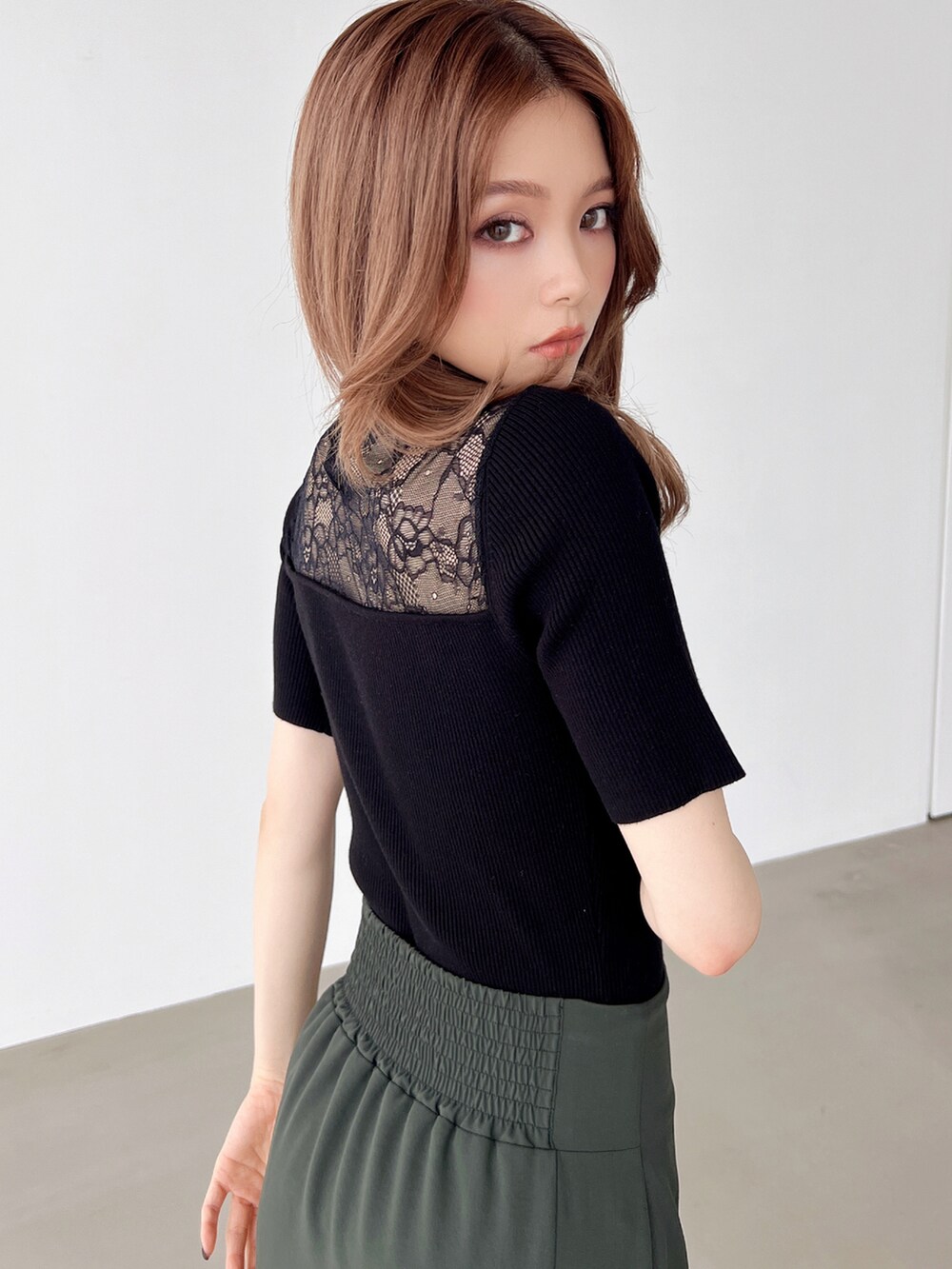 グリーン系のスカート、ブラック系のパンプス、ブラック系のニット/セーターを着用したレディースの夏コーディネートの2枚目の写真