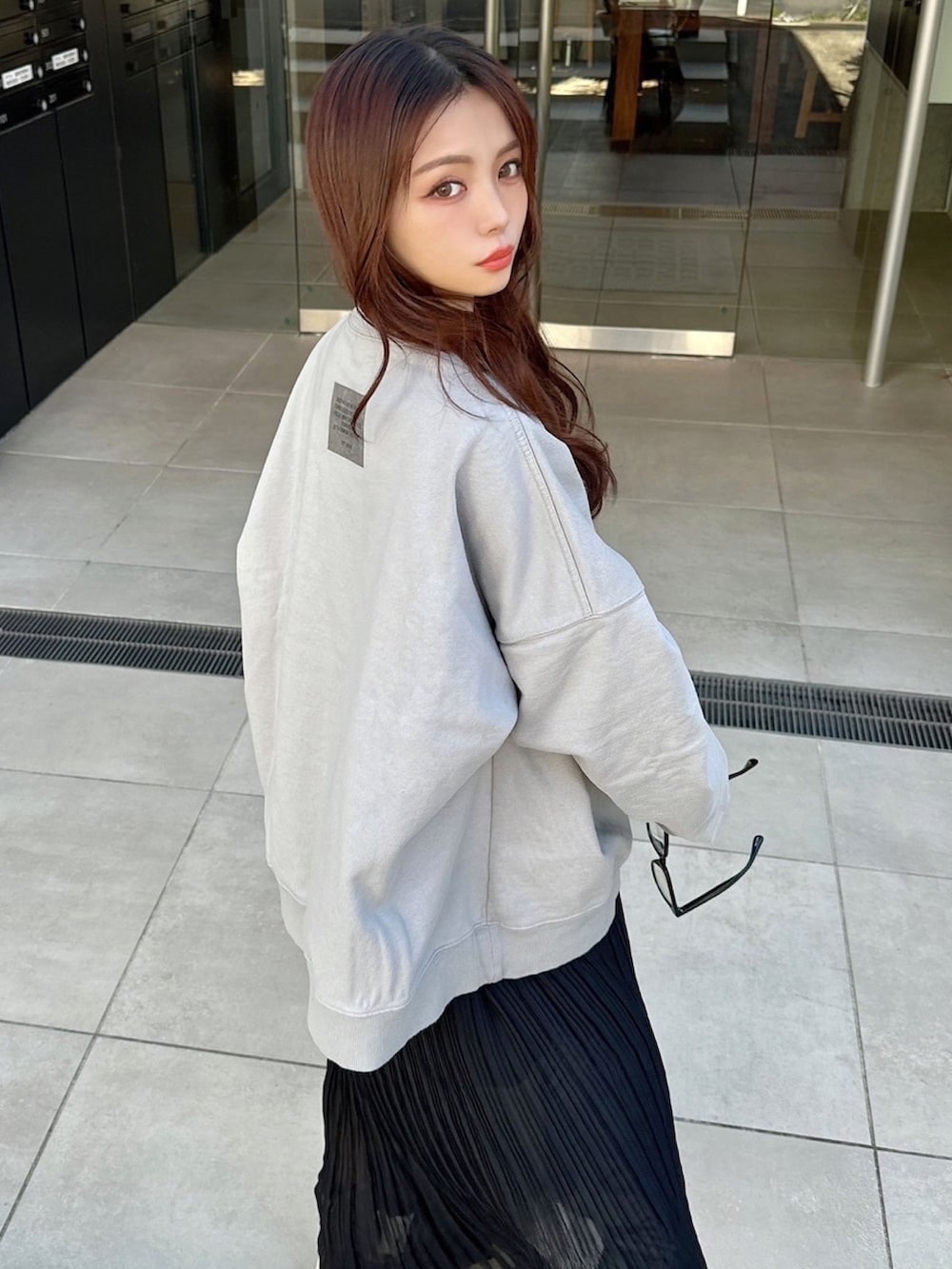 グレー系のスウェット、ブラック系のスカートを着用したレディースの春コーディネートの2枚目の写真