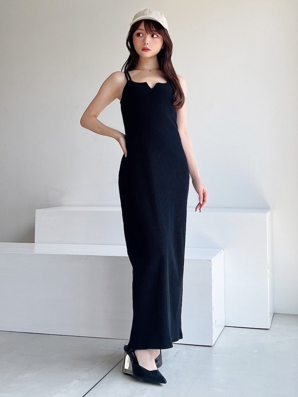 ブラック系のワンピース、ブラック系のサンダル、ホワイト系のキャップを着用したレディースの夏コーディネートの2枚目の写真