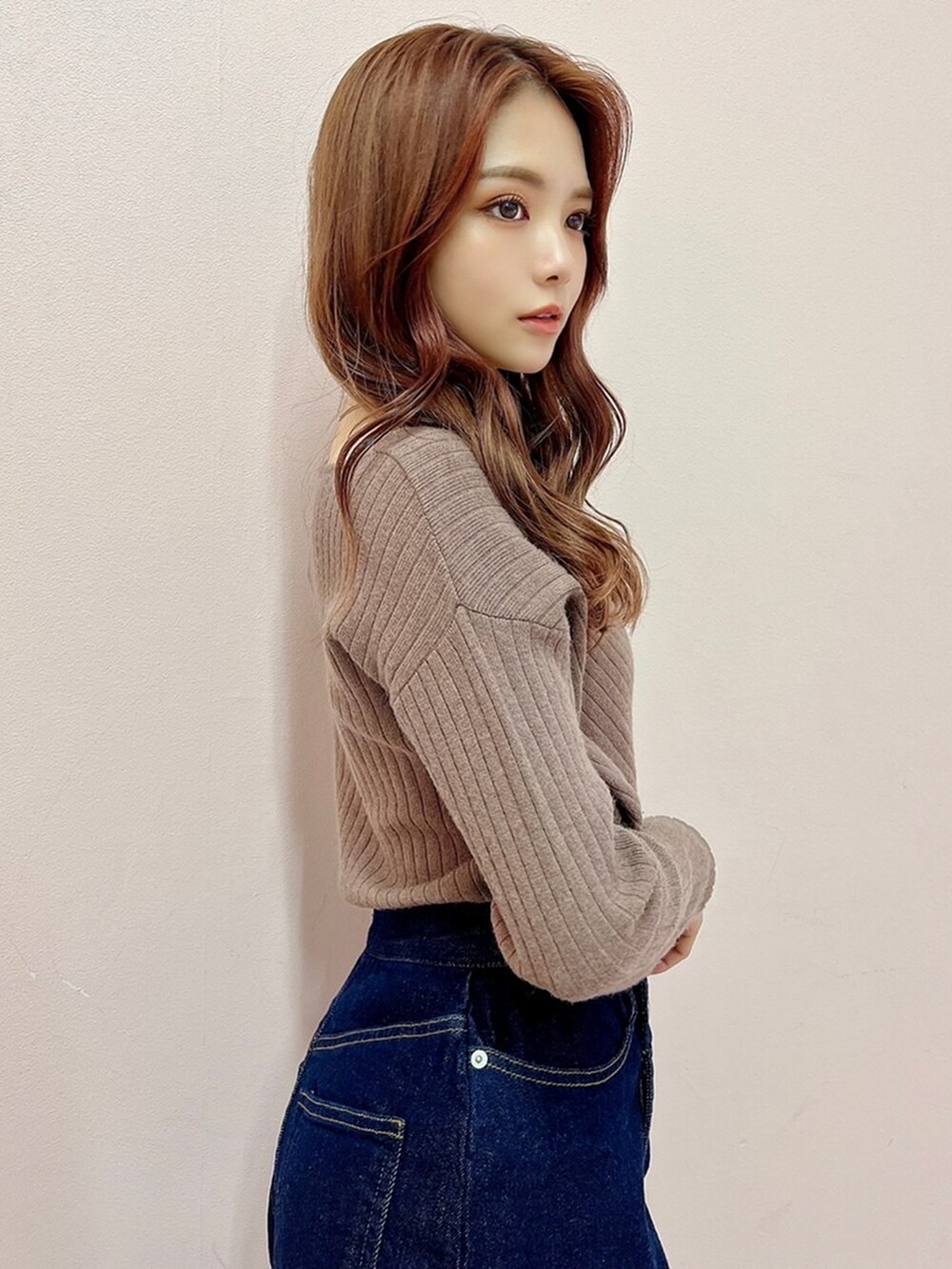 ブルー系のスカート、ブラック系のブーツ、ベージュ系のニット/セーターを着用したレディースの秋コーディネートの4枚目の写真