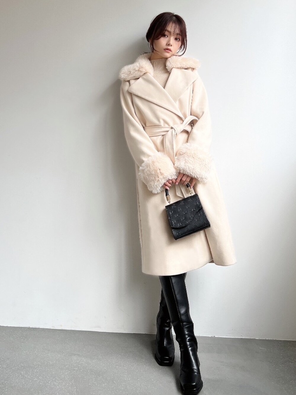 ホワイト系のその他アウター、ベージュ系のニット/セーター、ブラック系のハンドバッグを着用したレディースの冬コーディネートの3枚目の写真