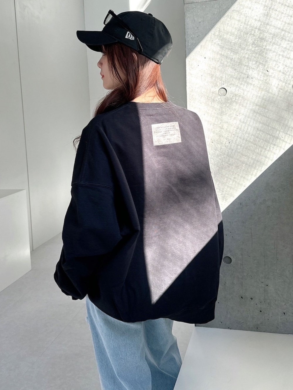 ブラック系のスウェット、ブルー系のデニムパンツを着用したレディースの春コーディネートの4枚目の写真