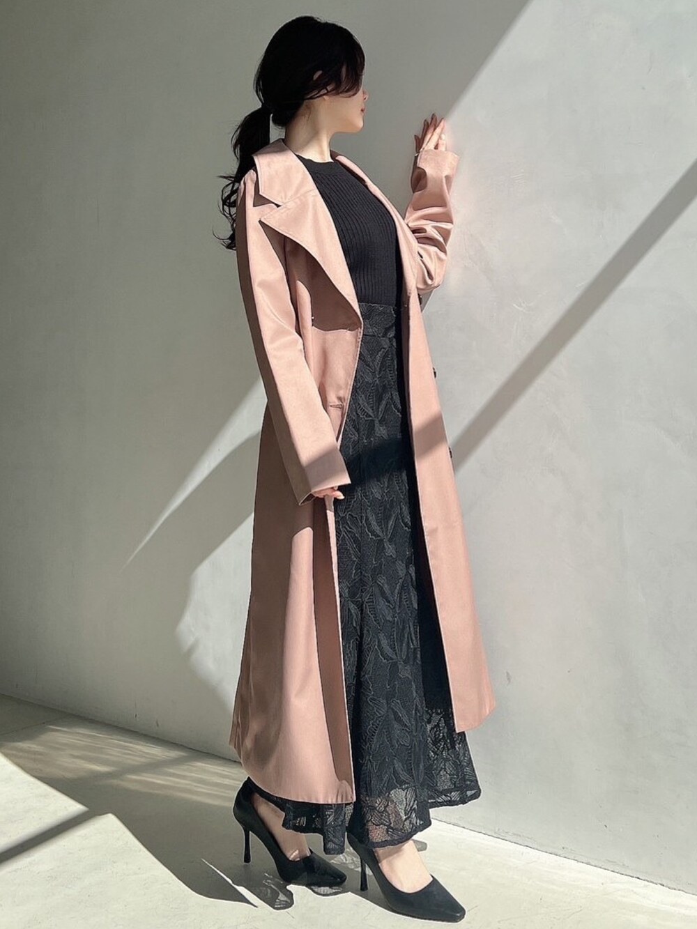 ブラック系のニット/セーター、ブラック系のスカート、ピンク系のトレンチコートを着用したレディースの春コーディネートの5枚目の写真