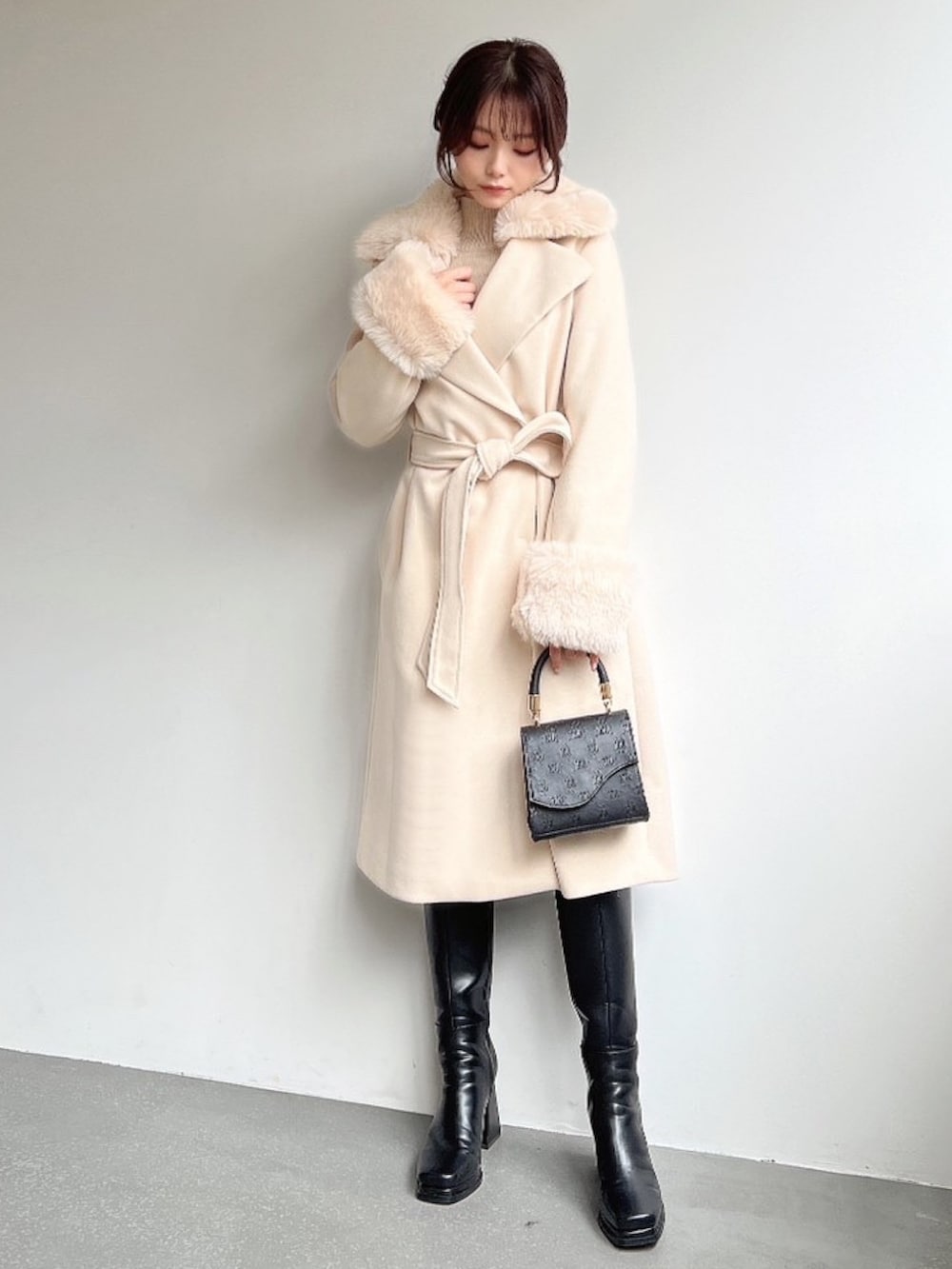 ホワイト系のその他アウター、ベージュ系のニット/セーター、ブラック系のハンドバッグを着用したレディースの冬コーディネートの4枚目の写真