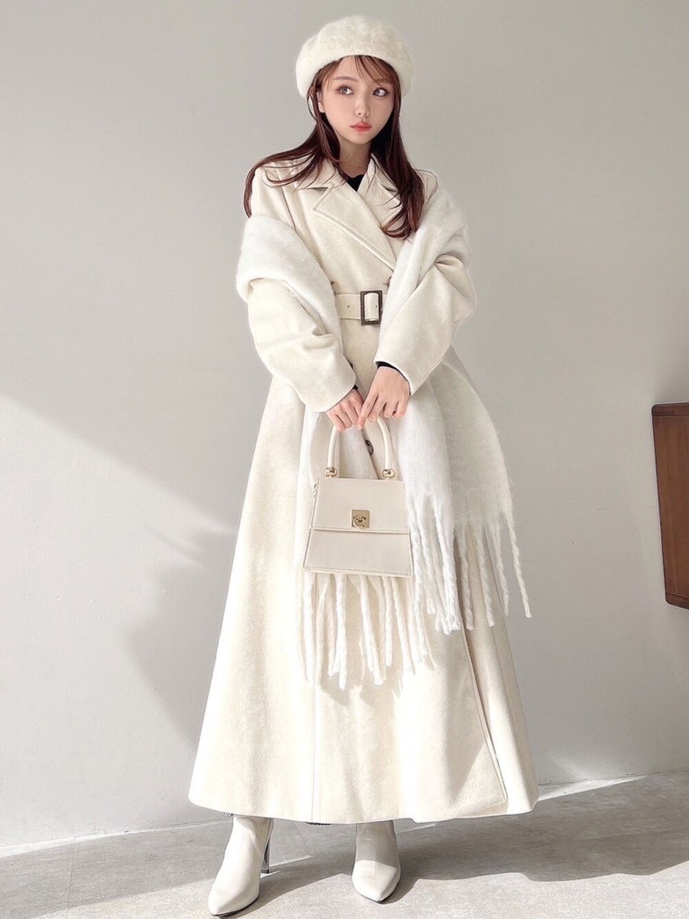 ホワイト系のチェスターコート、ホワイト系のハンドバッグ、ホワイト系のブーツを着用したレディースの秋コーディネートの3枚目の写真