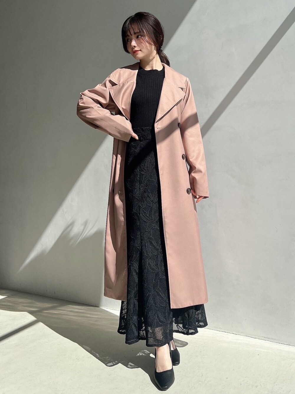 ブラック系のニット/セーター、ブラック系のスカート、ピンク系のトレンチコートを着用したレディースの春コーディネートの4枚目の写真