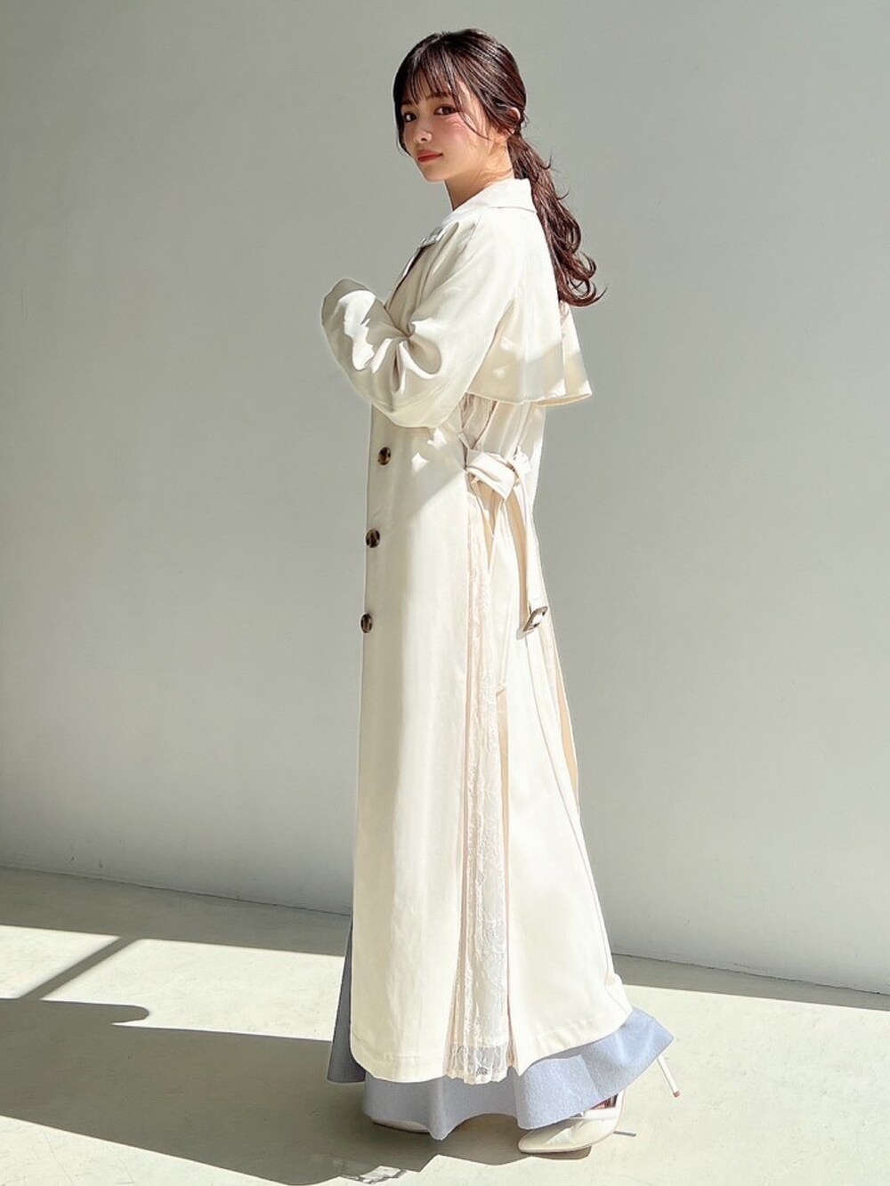 ブルー系のワンピース、ホワイト系のトレンチコートを着用したレディースの冬コーディネートの6枚目の写真