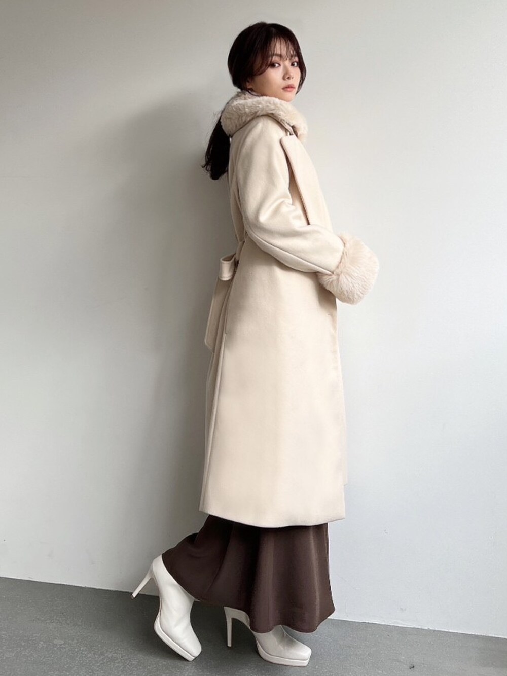 ホワイト系のその他アウター、ベージュ系のニット/セーター、ブラウン系のスカートを着用したレディースの冬コーディネートの2枚目の写真