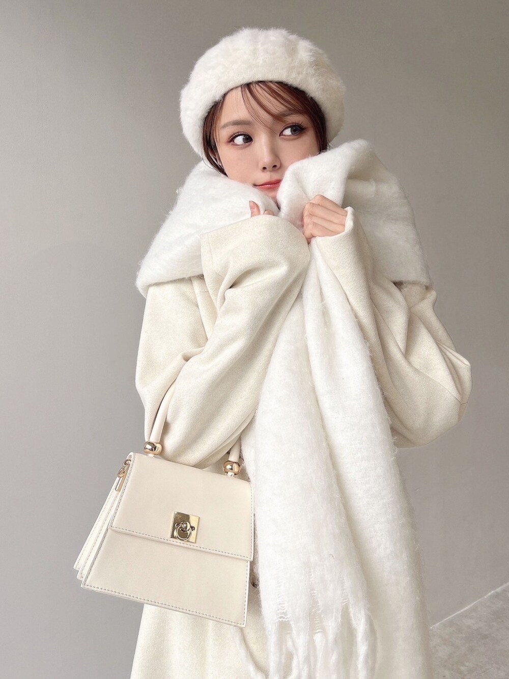 ホワイト系のチェスターコート、ホワイト系のハンドバッグ、ホワイト系のブーツを着用したレディースの秋コーディネートの4枚目の写真