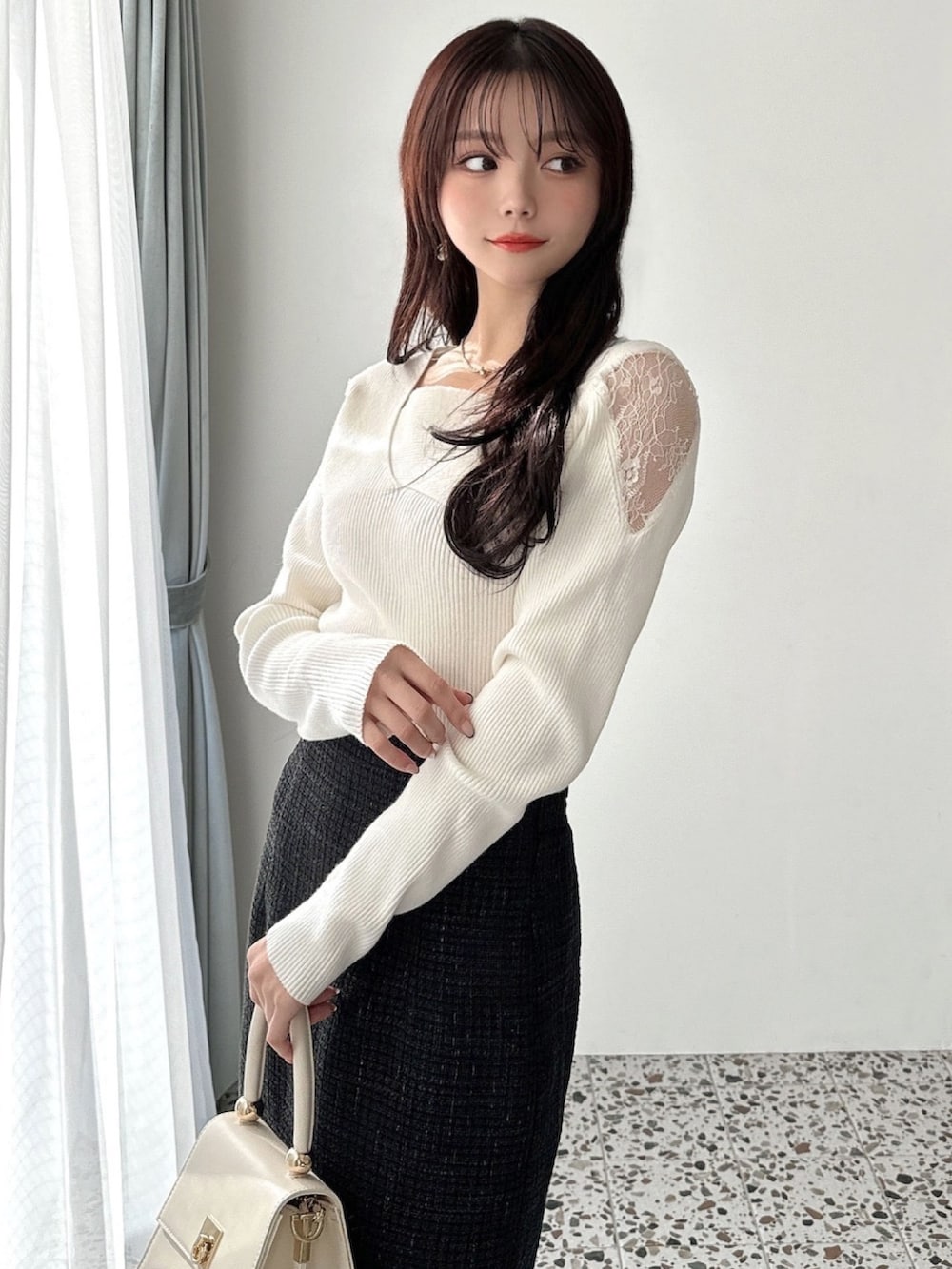 ホワイト系のニット/セーター、ブラック系のスカート、ホワイト系のハンドバッグを着用したレディースの冬コーディネートの3枚目の写真