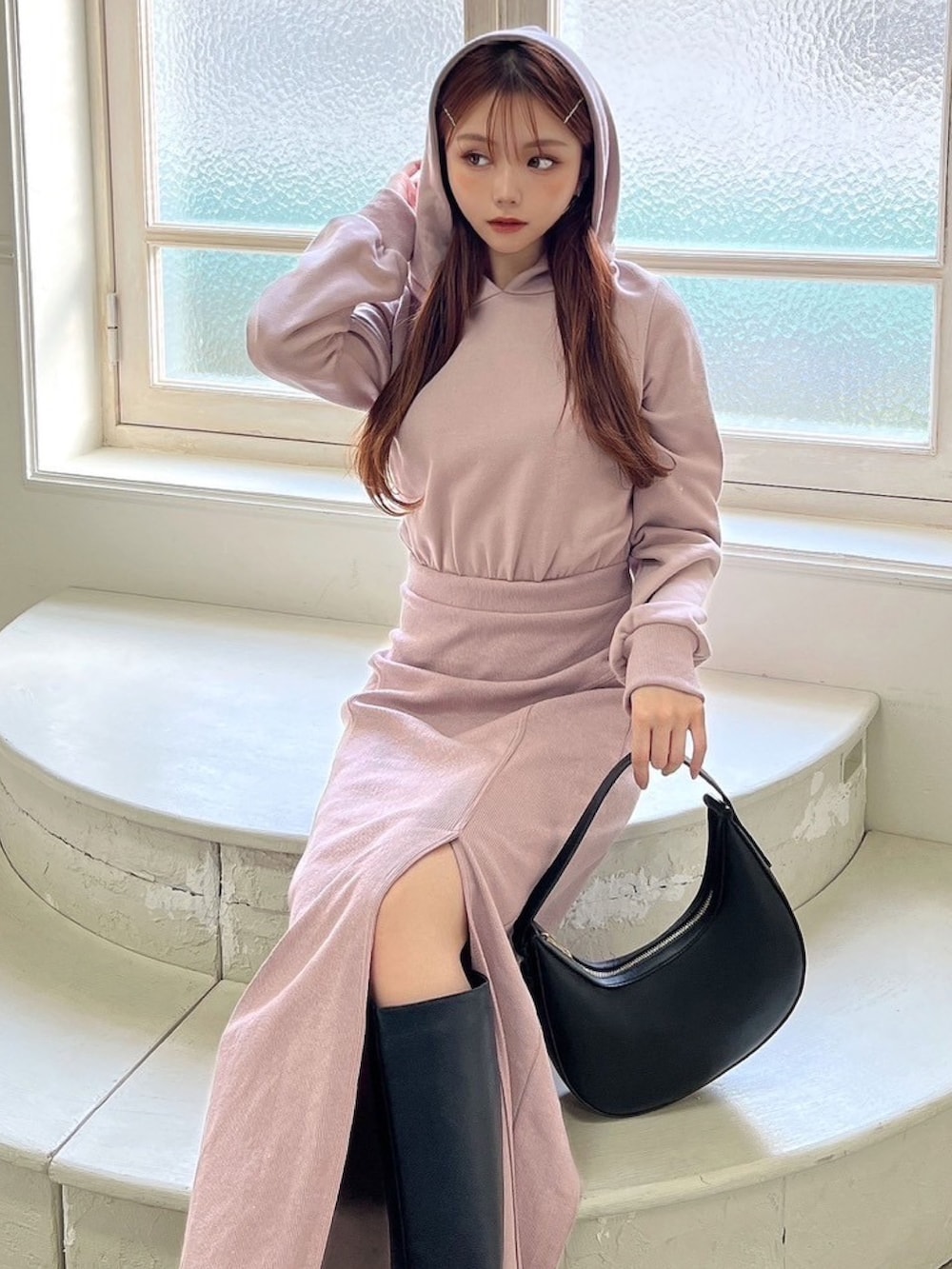 ピンク系のワンピース、ブラック系のハンドバッグ、ブラック系のブーツを着用したレディースの冬コーディネートの2枚目の写真