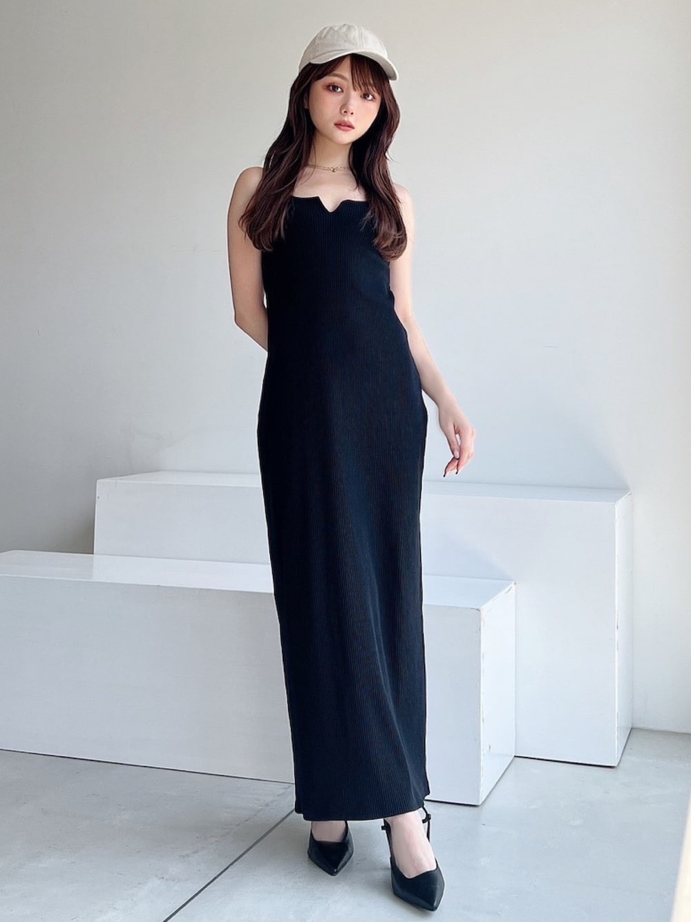 ブラック系のワンピース、ブラック系のサンダル、ホワイト系のキャップを着用したレディースの夏コーディネートの3枚目の写真