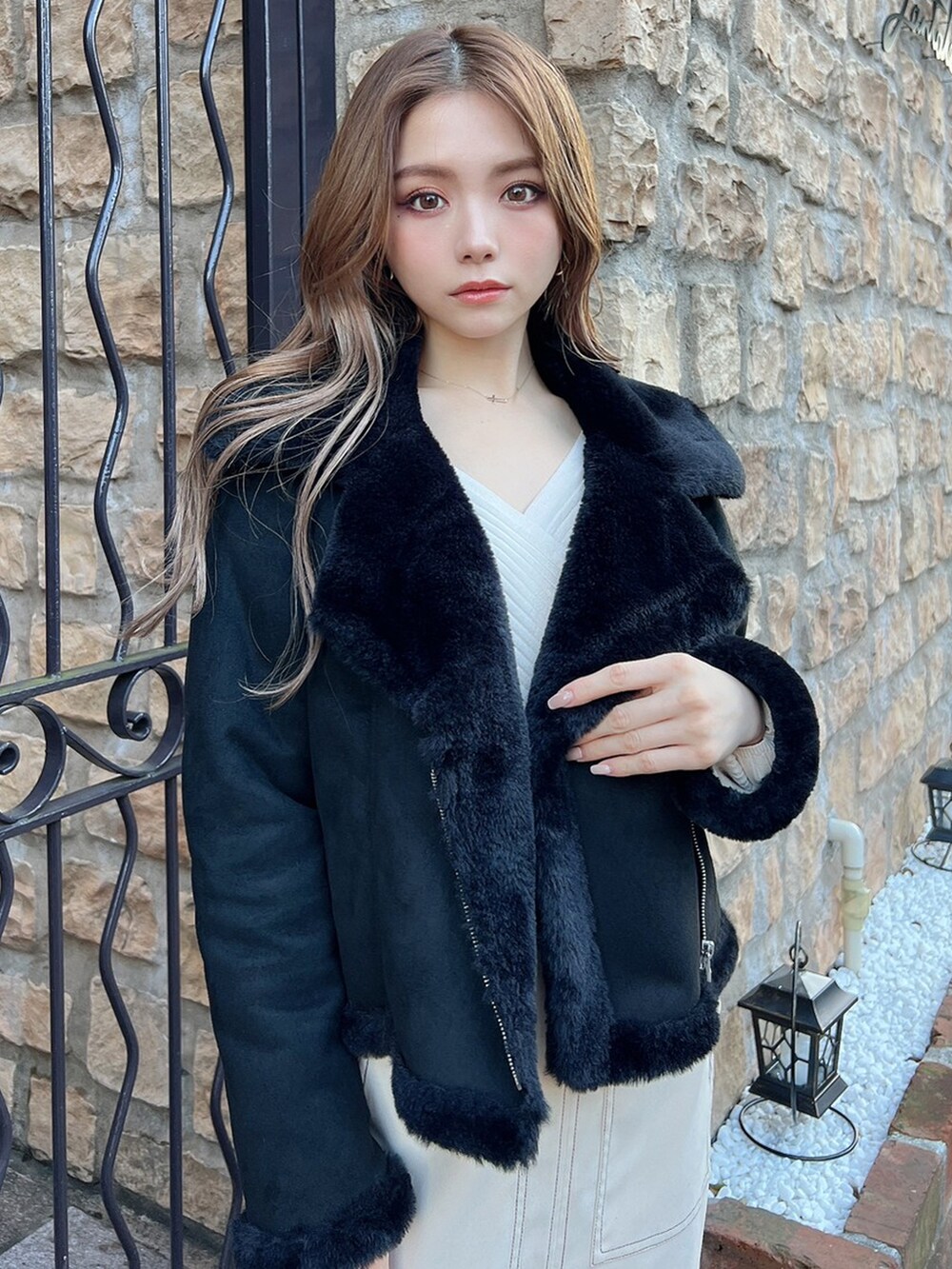 ホワイト系のスカート、ブラック系のブルゾン、ブラック系のブーツを着用したレディースの冬コーディネートの2枚目の写真