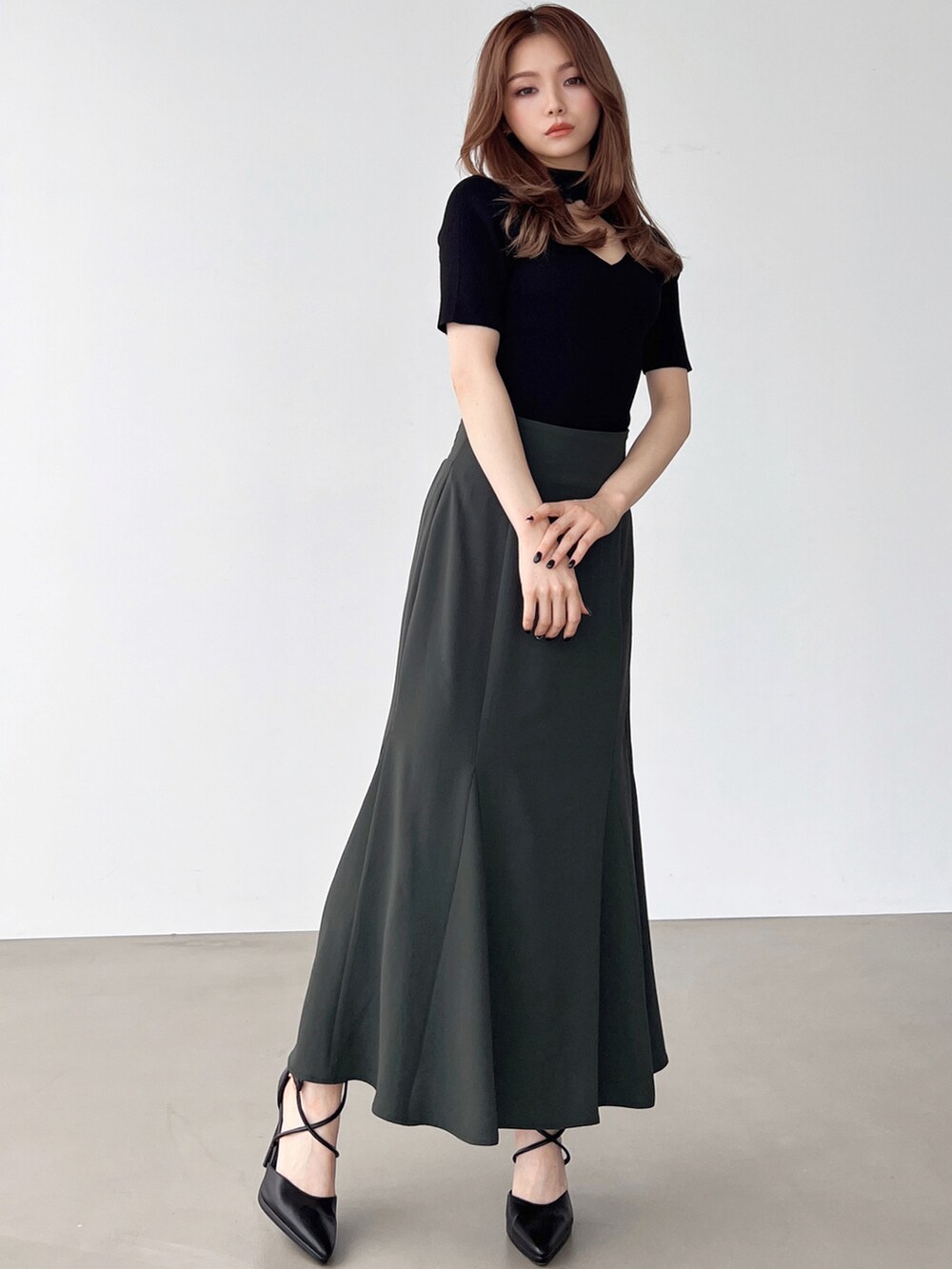 グリーン系のスカート、ブラック系のパンプス、ブラック系のニット/セーターを着用したレディースの夏コーディネートの4枚目の写真