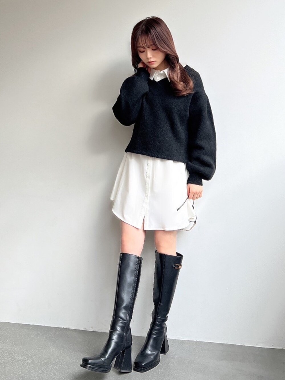 ブラック系のニット/セーター、ホワイト系のワンピース、ブラック系のブーツを着用したレディースの冬コーディネートの3枚目の写真