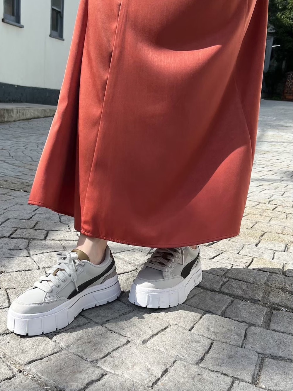 グレー系のスニーカー、ホワイト系のニット/セーター、オレンジ系のスカートを着用したレディースの冬コーディネートの6枚目の写真