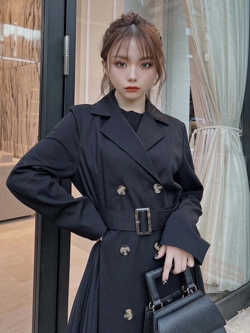 ブラック系のトレンチコート、ブラック系のワンピース、ブラック系のブーツを着用したレディースの冬コーディネートの5枚目の写真