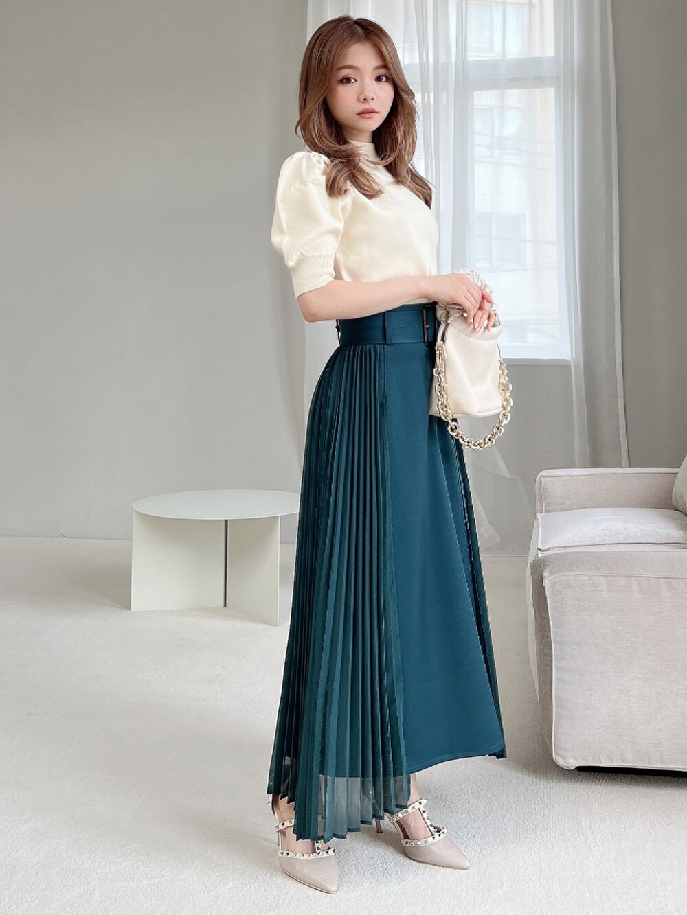 グリーン系のスカート、ホワイト系のニット/セーター、ホワイト系のハンドバッグを着用したレディースの夏コーディネートの2枚目の写真