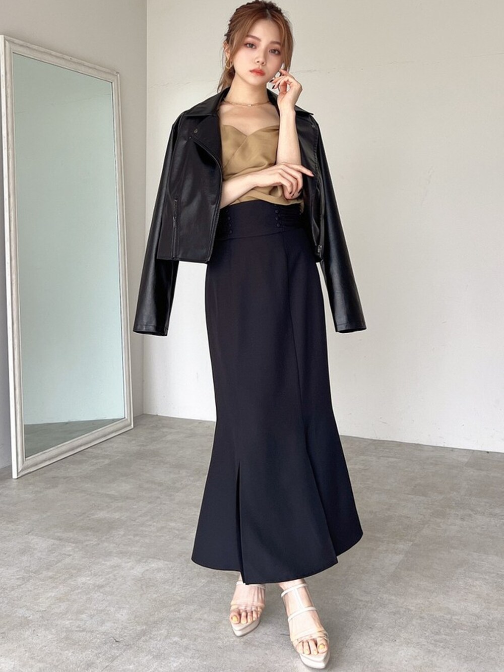 ブラック系のライダースジャケット、イエロー系のキャミソール、ブラック系のスカートを着用したレディースの夏コーディネートの2枚目の写真