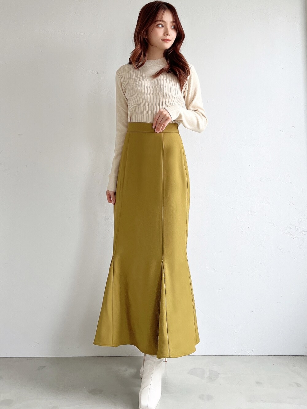 ブラウン系のスカート、ホワイト系のニット/セーター、ブラック系のチェスターコートを着用したレディースの冬コーディネートの3枚目の写真