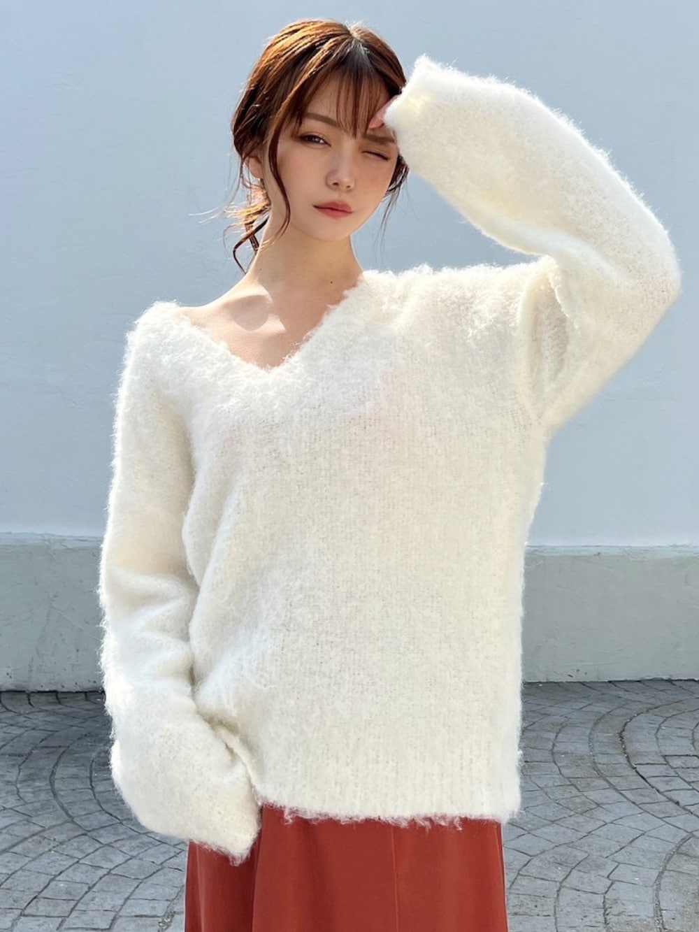 グレー系のスニーカー、ホワイト系のニット/セーター、オレンジ系のスカートを着用したレディースの冬コーディネートの4枚目の写真