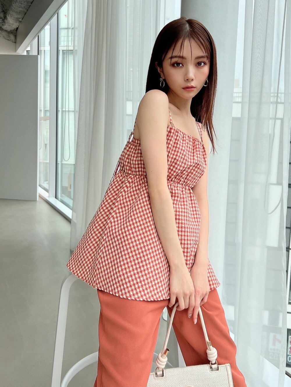 オレンジ系のキャミソール、オレンジ系のその他パンツ、ホワイト系のハンドバッグを着用したレディースの春コーディネートの2枚目の写真