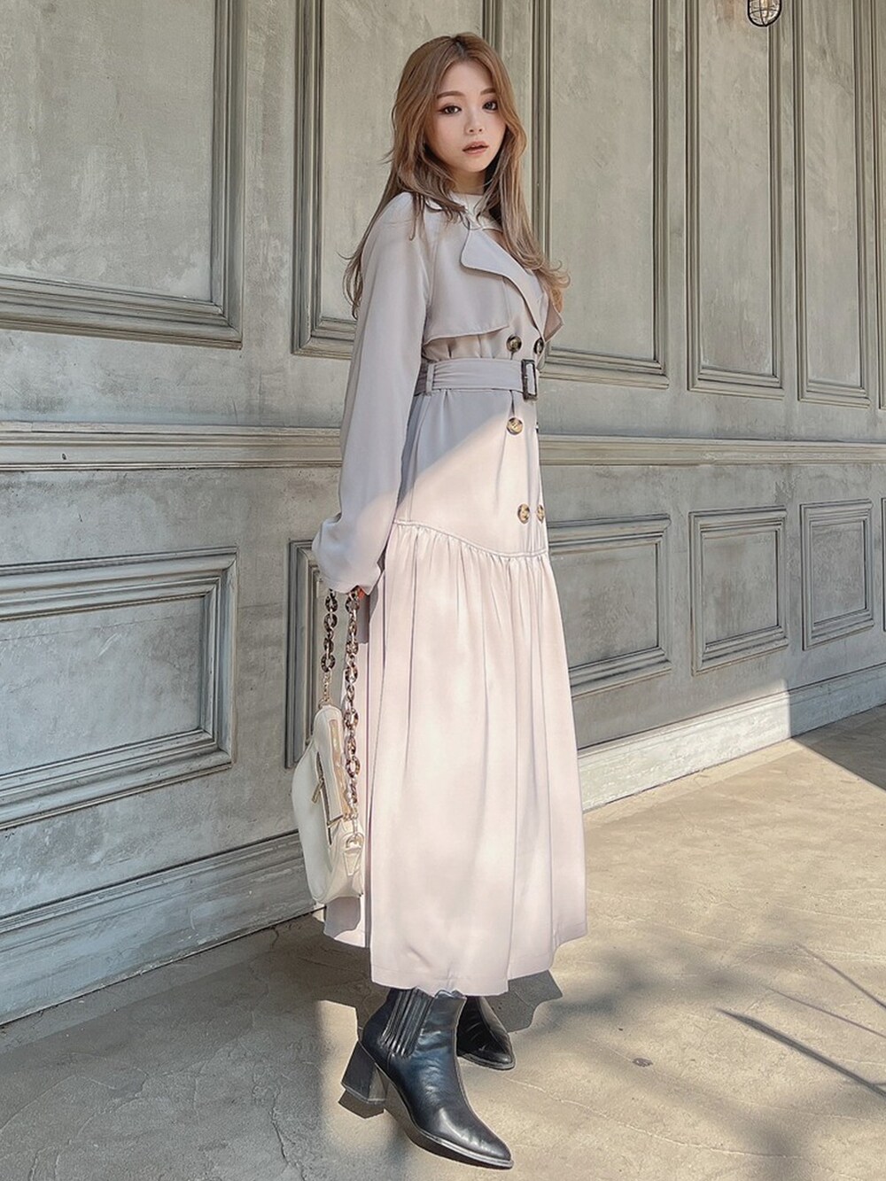 ホワイト系のトレンチコート、ホワイト系のニット/セーター、ブラウン系のブーツを着用したレディースの春コーディネートの2枚目の写真