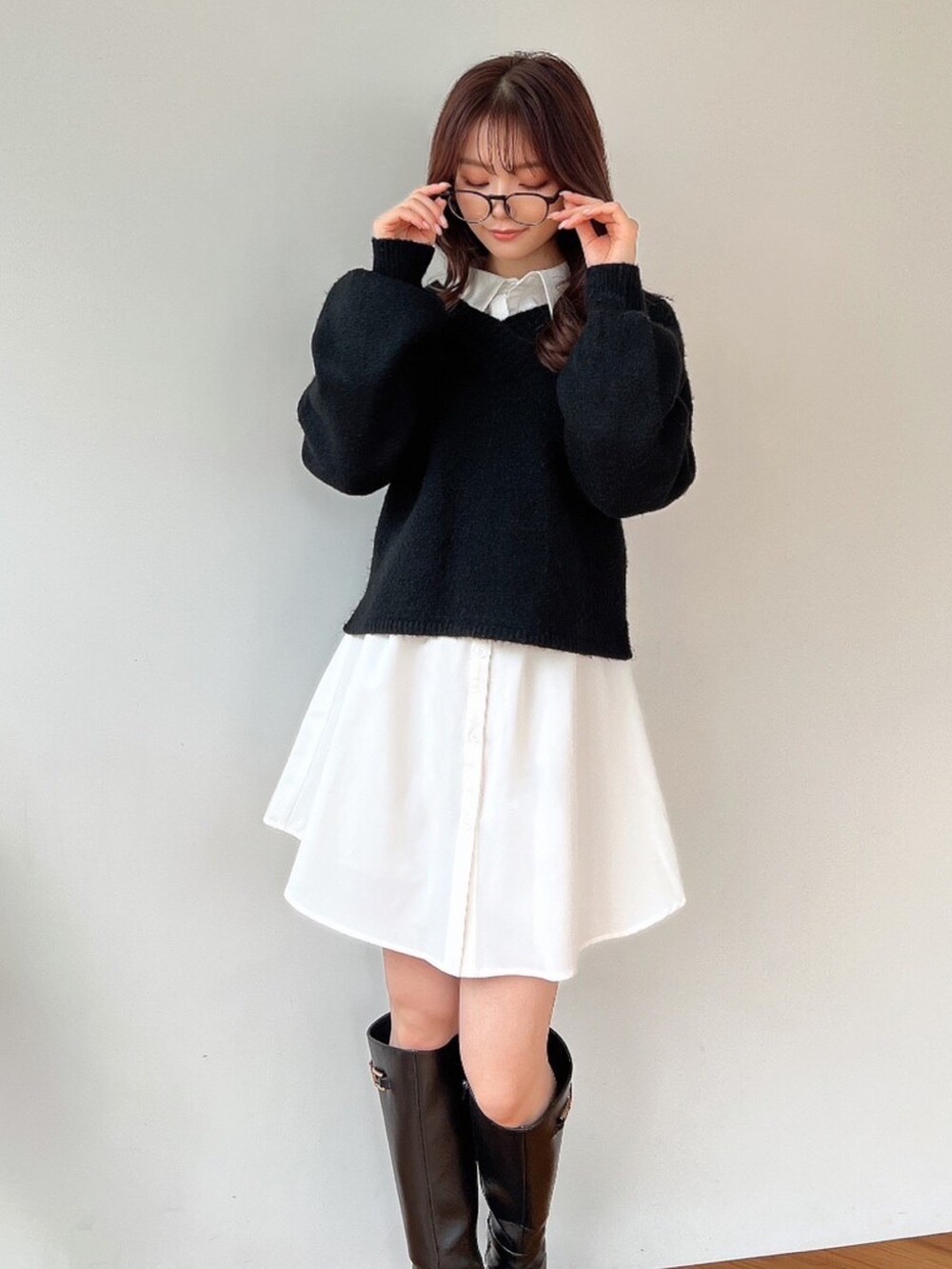 ブラック系のニット/セーター、ホワイト系のワンピース、ブラック系のブーツを着用したレディースの冬コーディネートの2枚目の写真