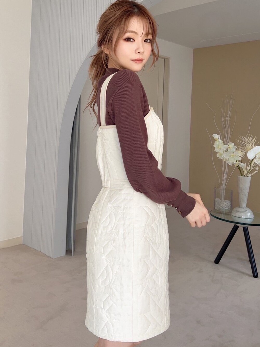 ホワイト系のワンピース、ホワイト系のパンプス、ブラウン系のニット/セーターを着用したレディースの秋コーディネートの2枚目の写真