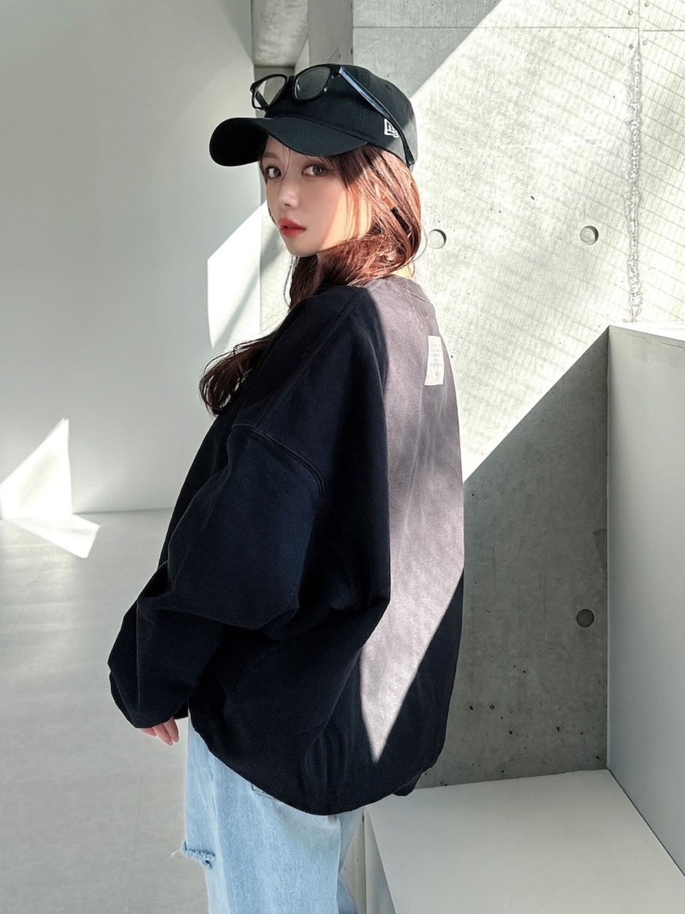 ブラック系のスウェット、ブルー系のデニムパンツを着用したレディースの春コーディネートの3枚目の写真