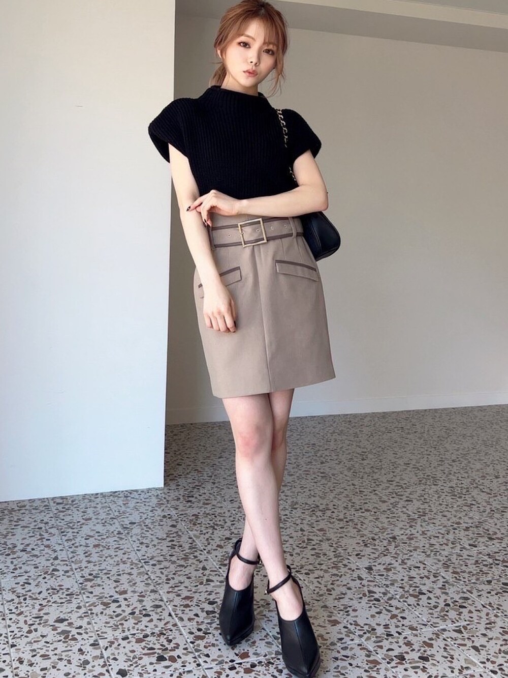 ベージュ系のスカート、ブラック系のショルダーバッグ、ブラック系のブーツを着用したレディースの夏コーディネートの3枚目の写真